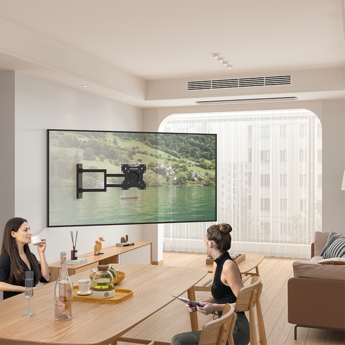 Zwei Frauen in einem modernen Wohnzimmer mit großem Fernseher an der Wand und Tisch.