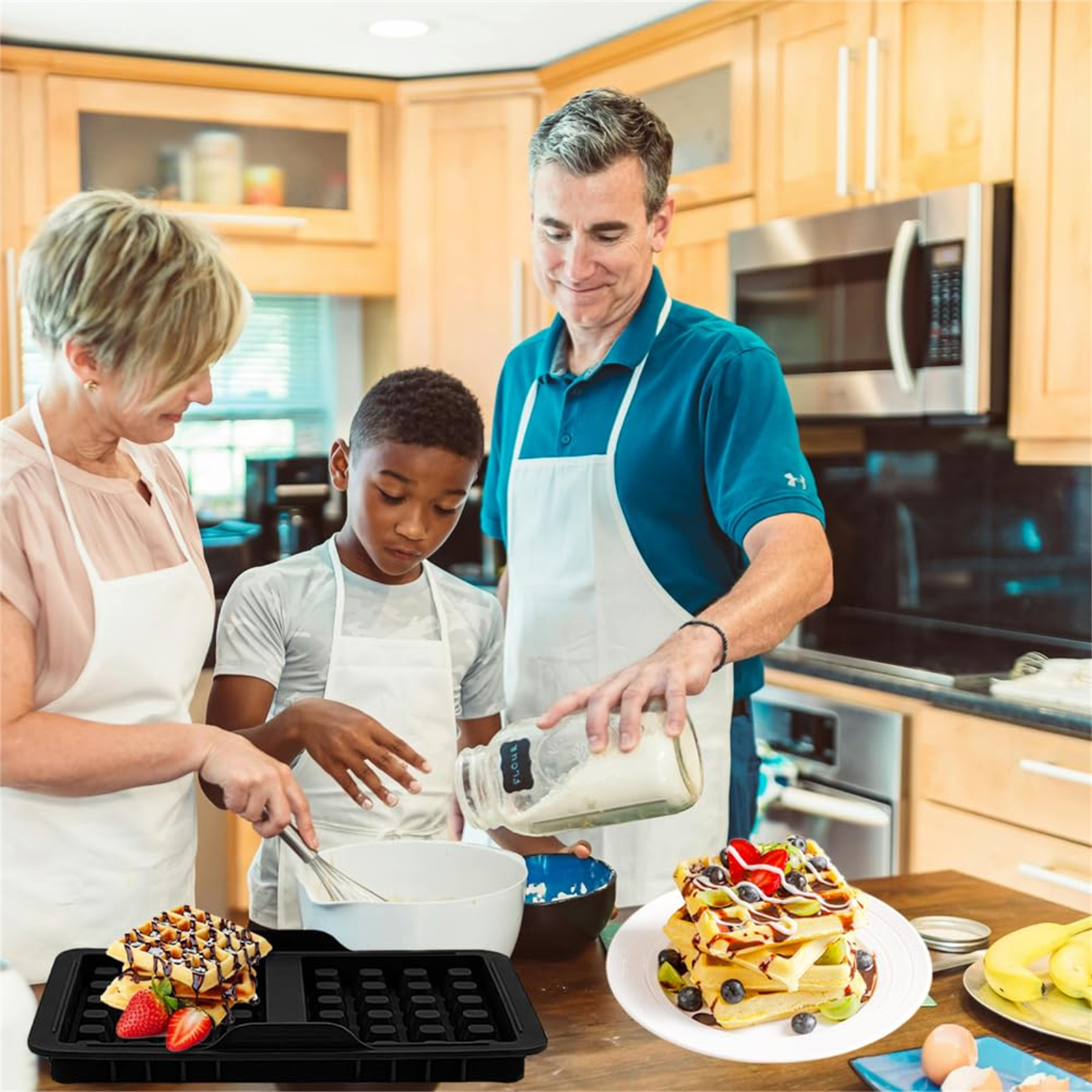 Familie bereitet Waffeln zu. Vater gießt Teig, Sohn verrührt, Waffeln auf Tablett, mit Obst.