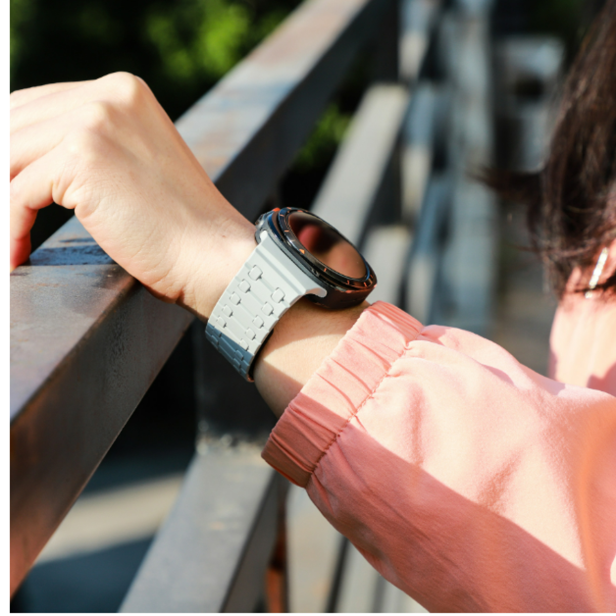 Persona che indossa uno smartwatch con cinturino bianco su un ponte.