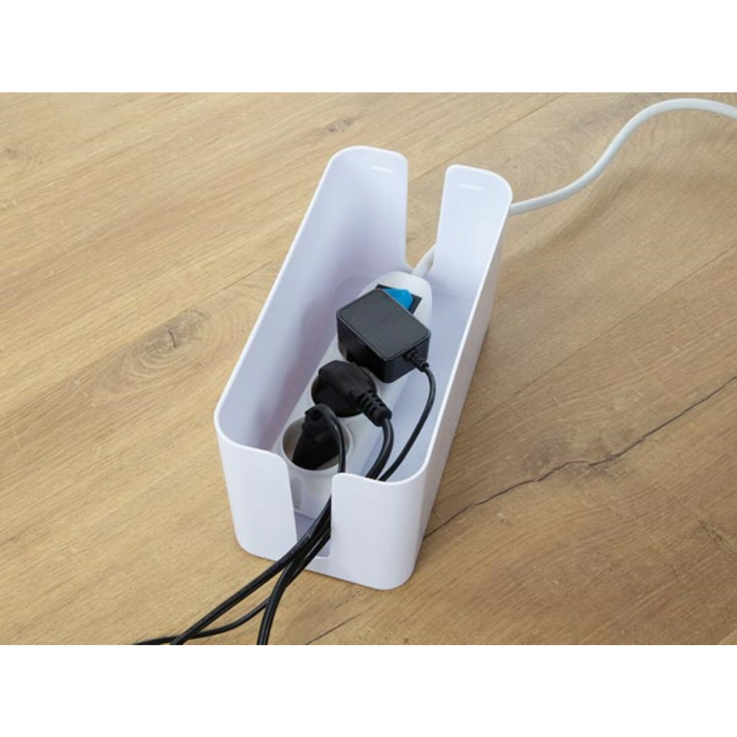 Biały organizer kabli z listwą zasilającą i kablami w środku. Kable wychodzą na zewnątrz.