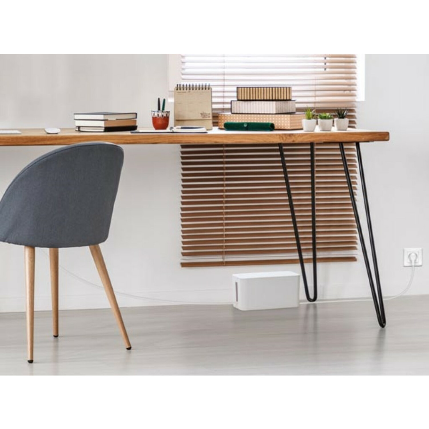 Drewniane biurko z czarnymi nogami. Szare krzesło i białe pudełko w scenie.