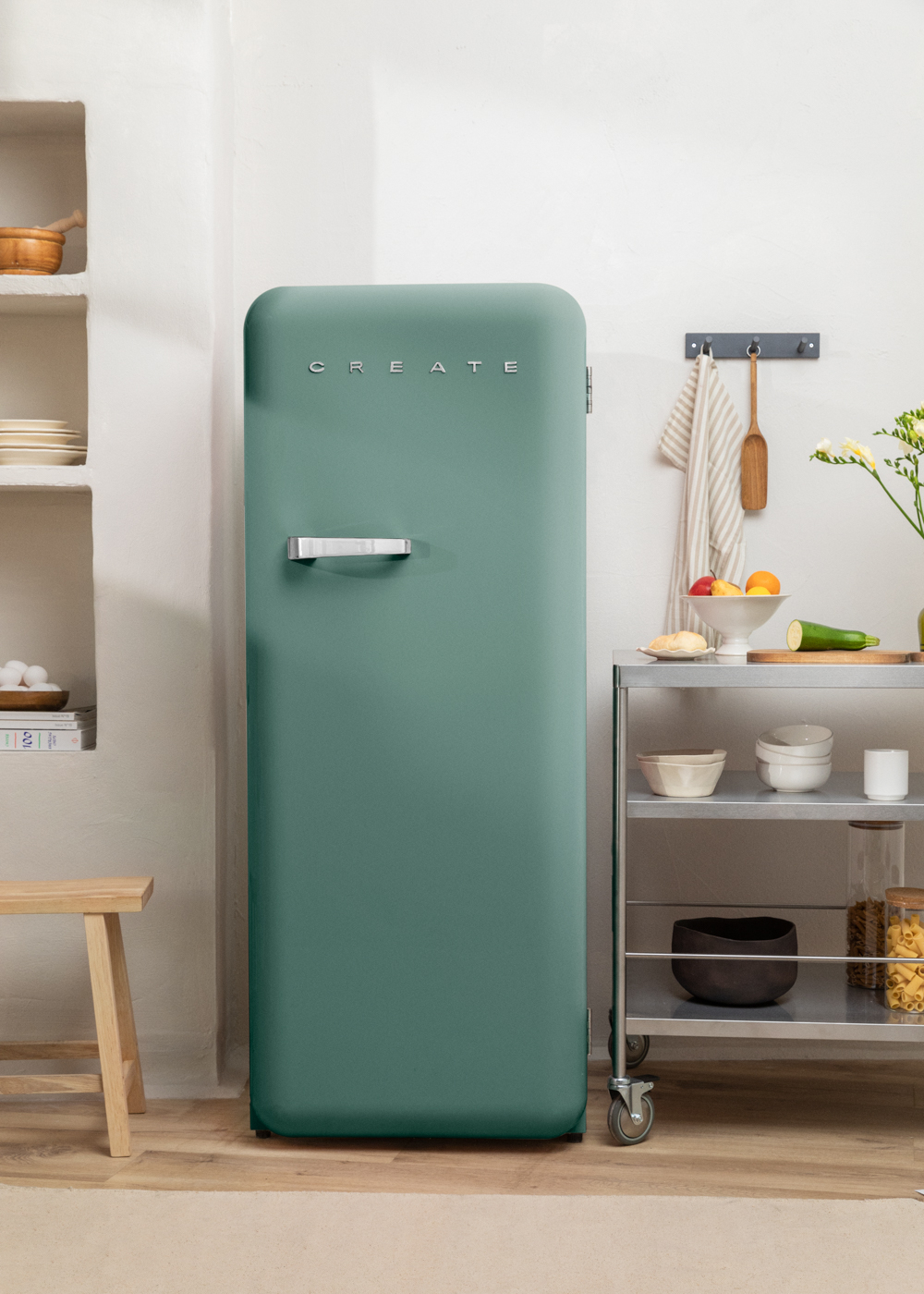 Refrigerador retro verde en cocina, con carrito y estanterías.