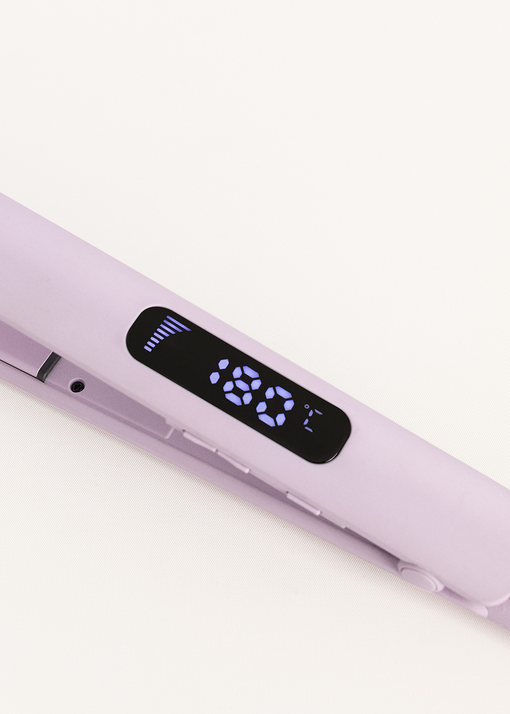 Un primer plano de una plancha para el pelo morada con una pantalla digital que muestra la temperatura.