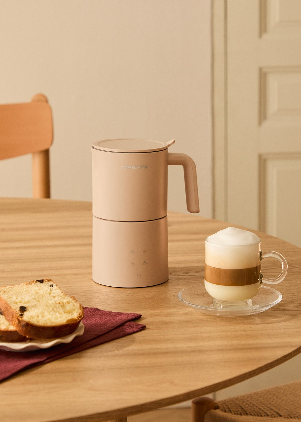 Cafetera rosa con café y pan en una mesa, con una servilleta roja.