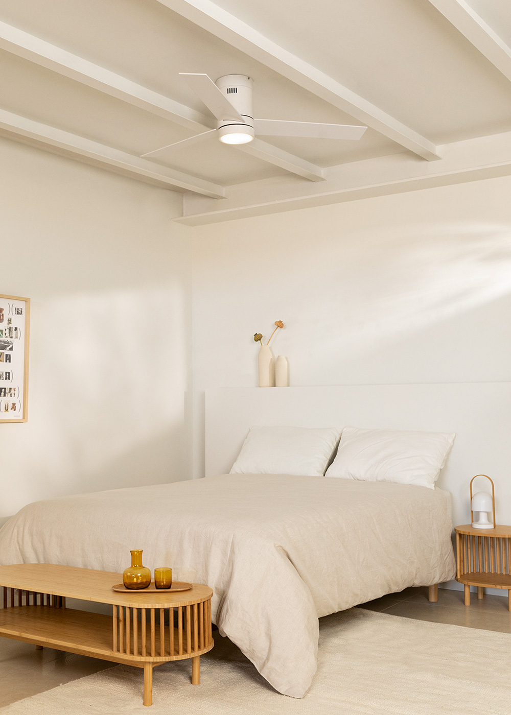 Dormitorio con cama, ventilador de techo y elementos decorativos en mesa.
