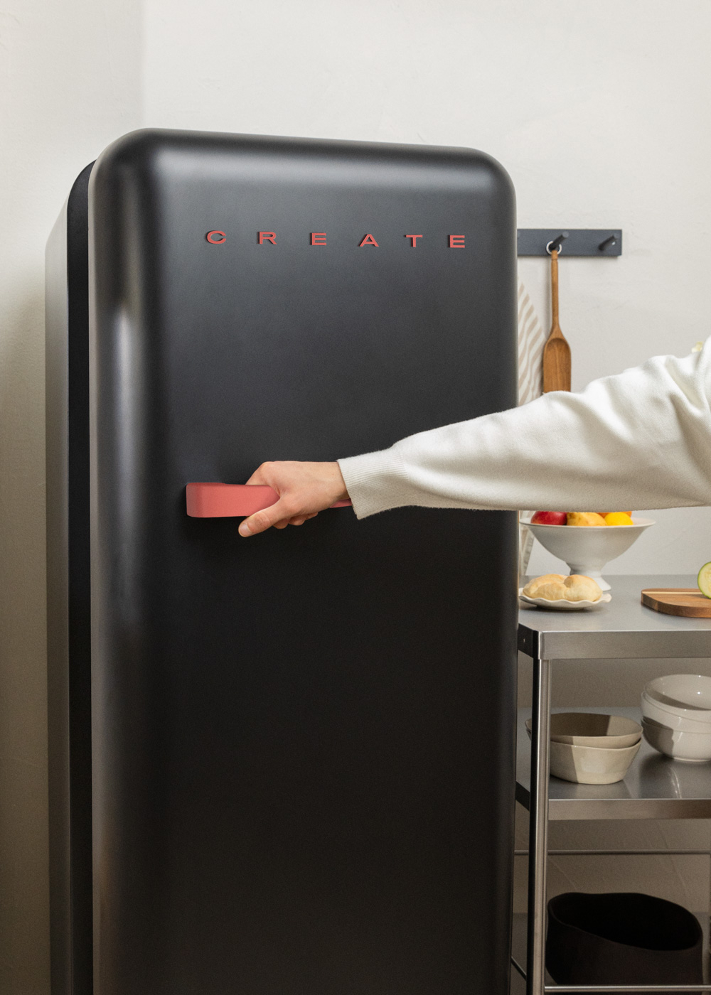 Persona abriendo un refrigerador CREATE negro en una cocina.
