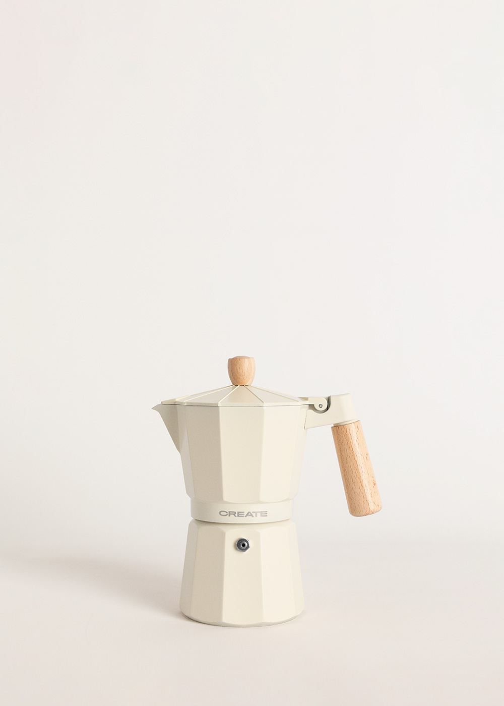 Máquina de espresso color crema con mango de madera. Fondo blanco. La palabra CREATE es visible.