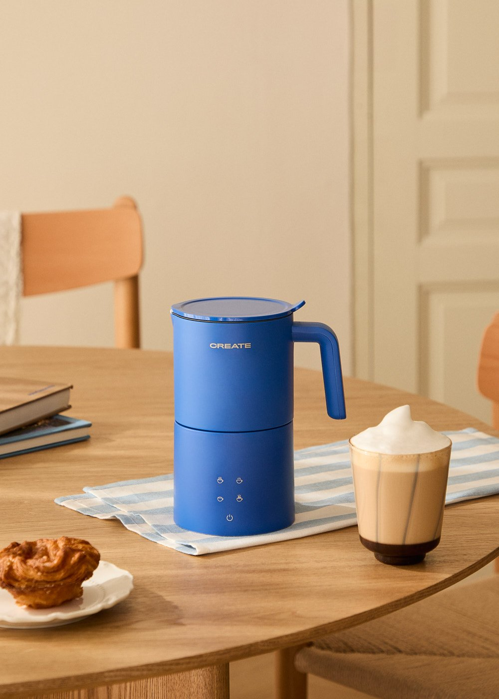 Cafetera azul con latte en mesa. También muffin y servilleta.