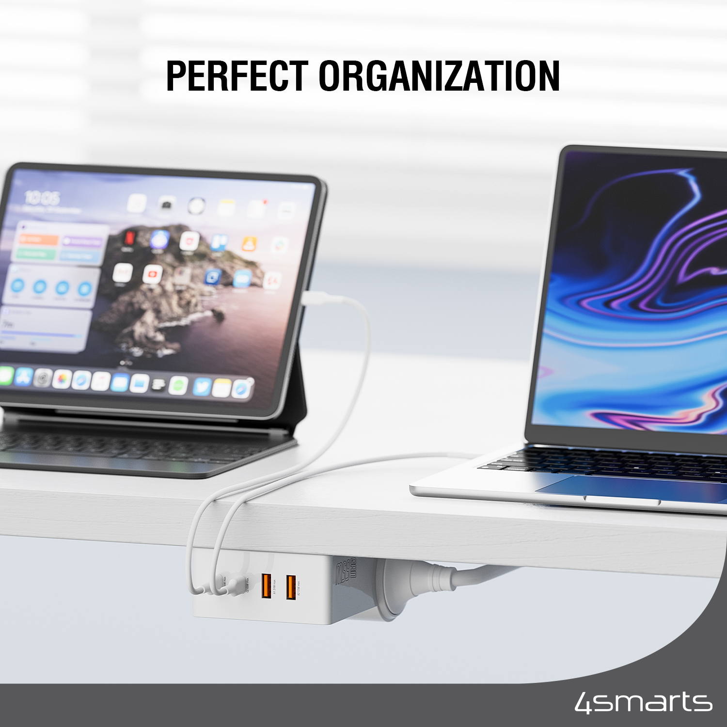 White desk with electronics, including a tablet, laptop, and a charging station.