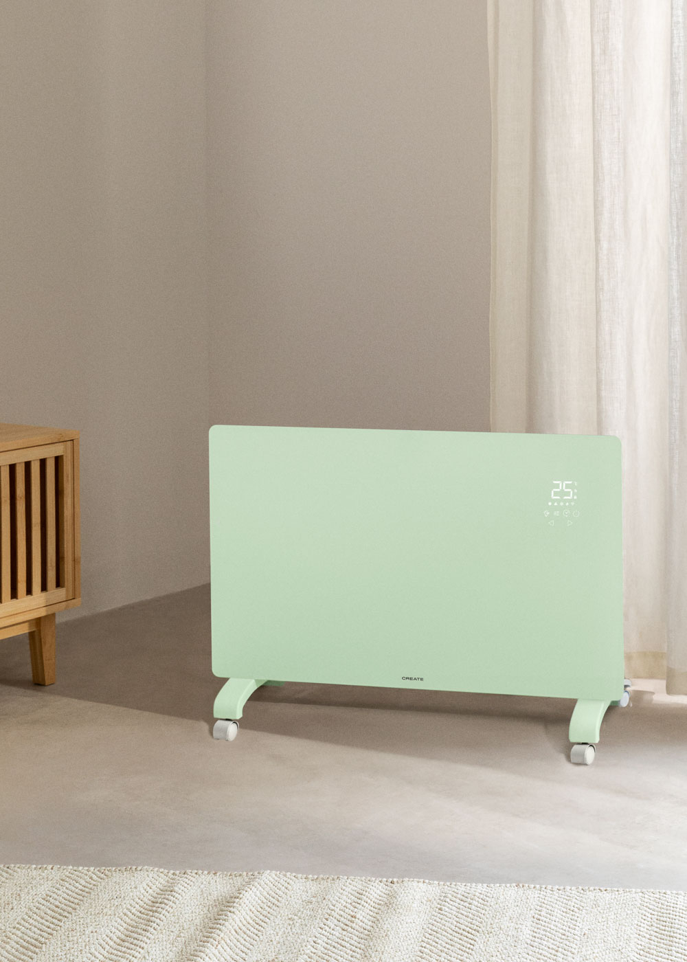 Calentador verde sobre ruedas. Pared beige, mueble de madera y ventana con cortina. Pantalla digital.