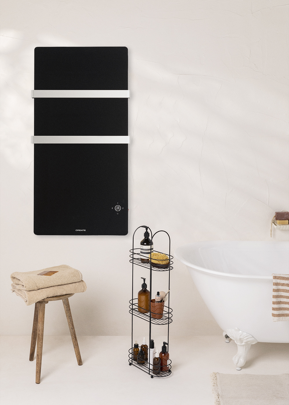 Calentador CREATE negro en pared, toallas en taburete, bañera blanca y baño.