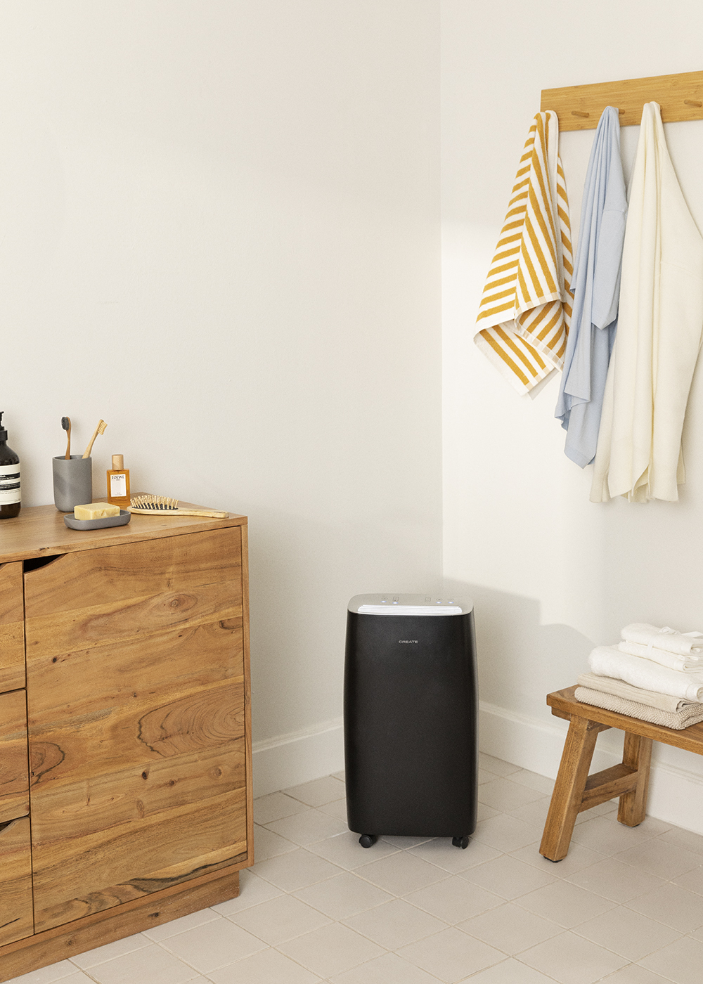 Baño con purificador de aire negro, mueble de madera y toallas.