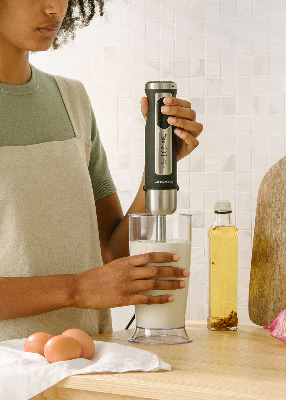 Una persona mezclando ingredientes en un vaso con una batidora de mano CREATE.