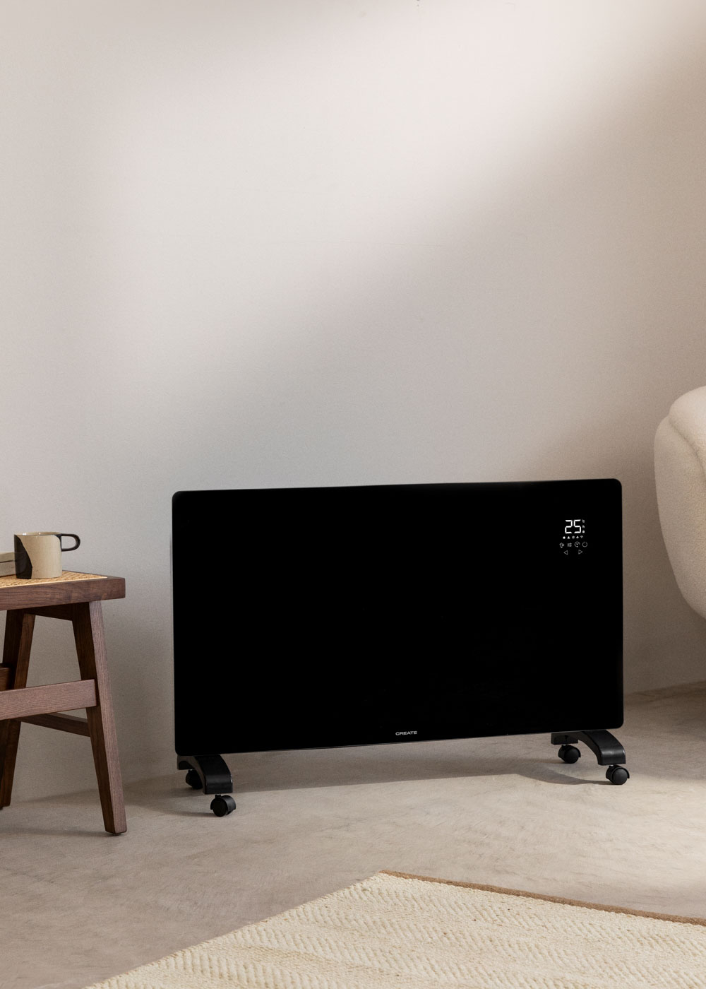 Calentador negro con pantalla, contra una pared blanca. Un taburete al lado.