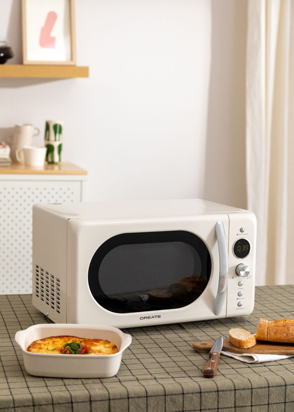Micro-ondes blanc cassé sur une table avec de la nourriture. Le nom CREATE est devant.