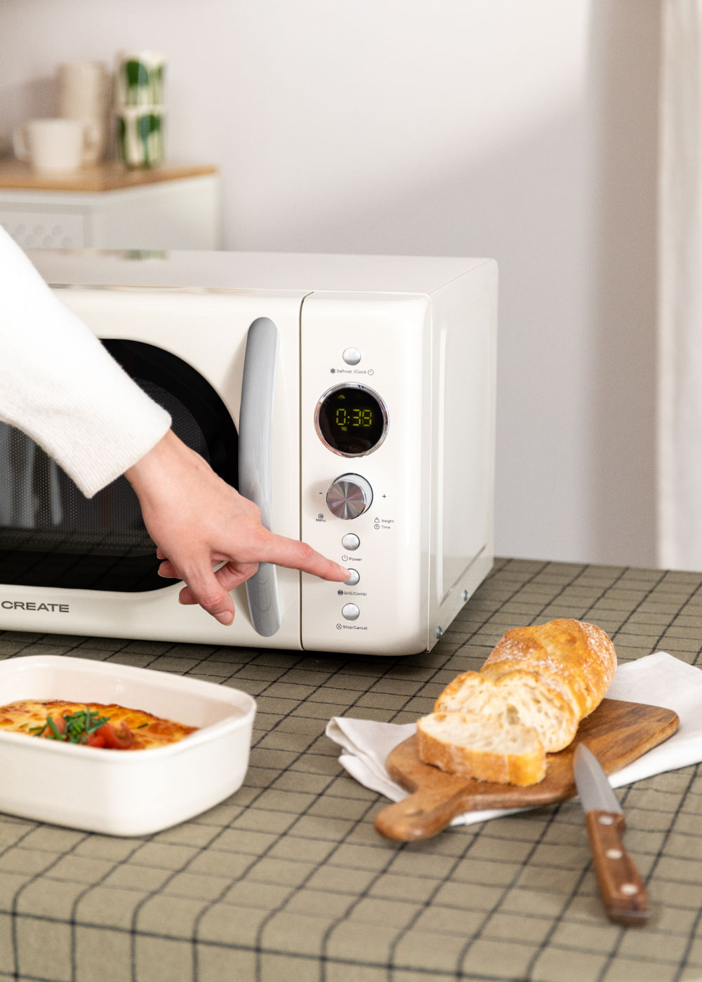 Personne utilise un four à micro-ondes. Du pain et un plat sont sur la table.