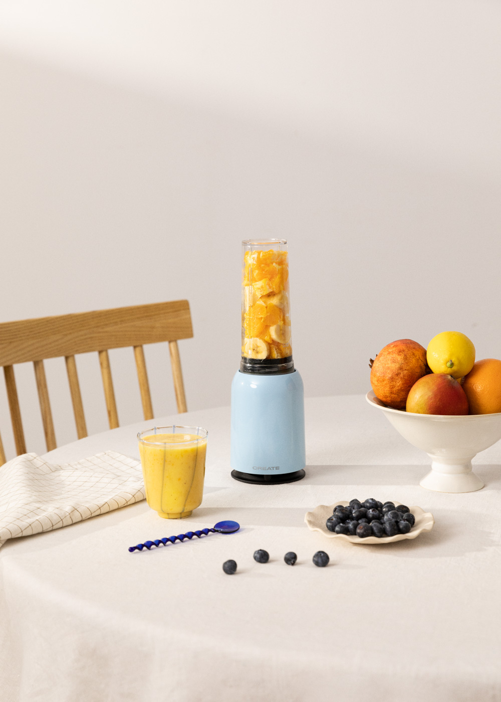 Mixer mit Früchten, Smoothie-Glas, Blaubeeren und Früchte auf einem Tisch.