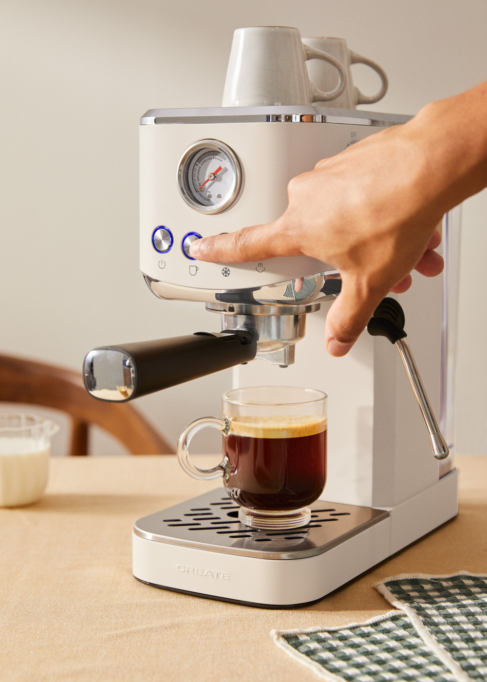 Una persona presionando el botón de encendido de una cafetera color crema.