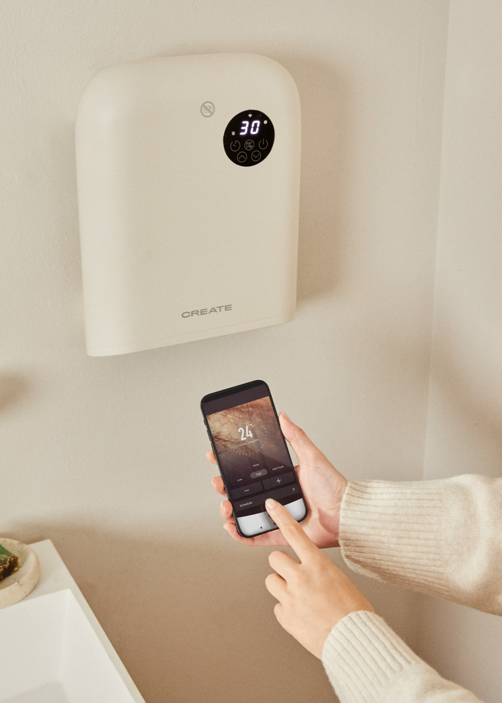 Una persona usa un teléfono para controlar un dispositivo de pared crema.