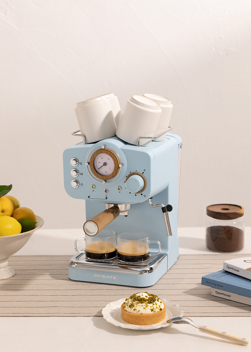 Máquina de espresso azul con dos tazas de café. Tarta y limones en la escena.