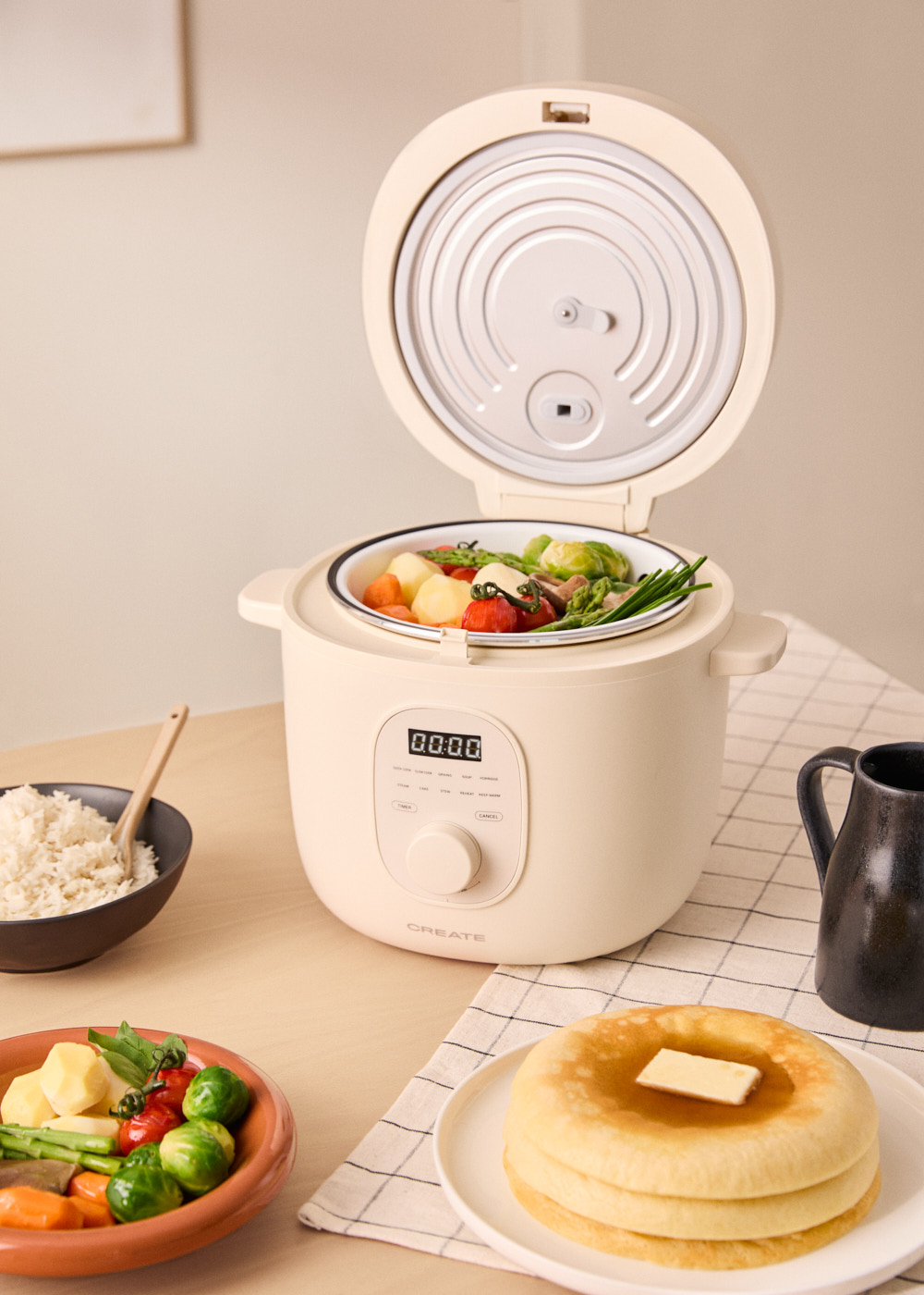 Multicocina color crema con comida cocinada dentro, y otros platos en mesa.