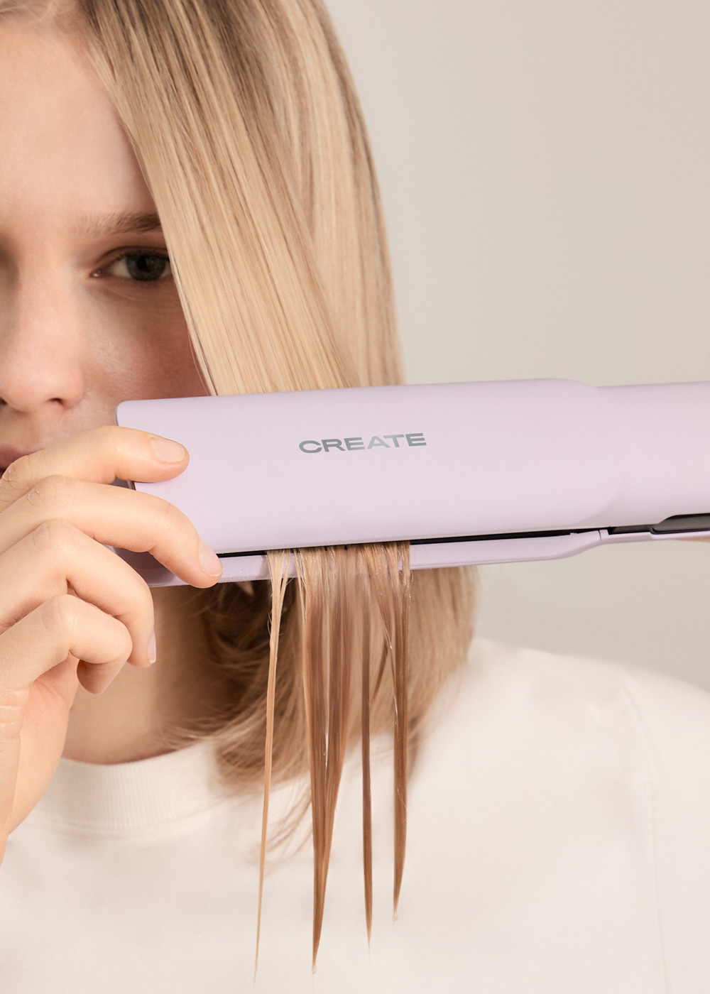 Una persona alisando cabello rubio con una plancha de pelo morada. El cabello se está alisando.