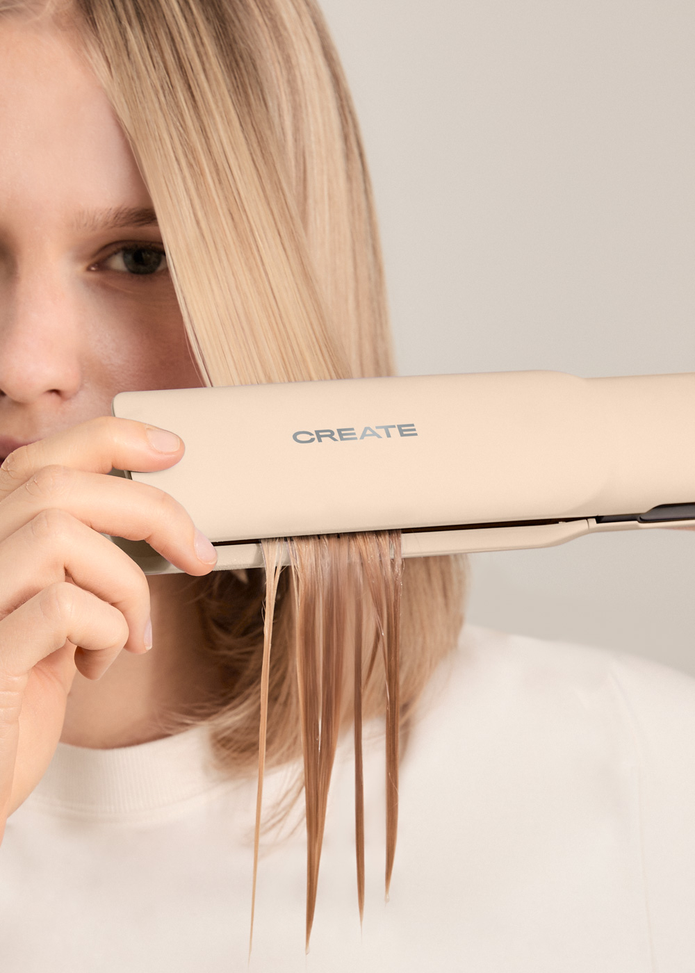 Persona usando una plancha de pelo crema. El pelo se alisa con la palabra CREATE.