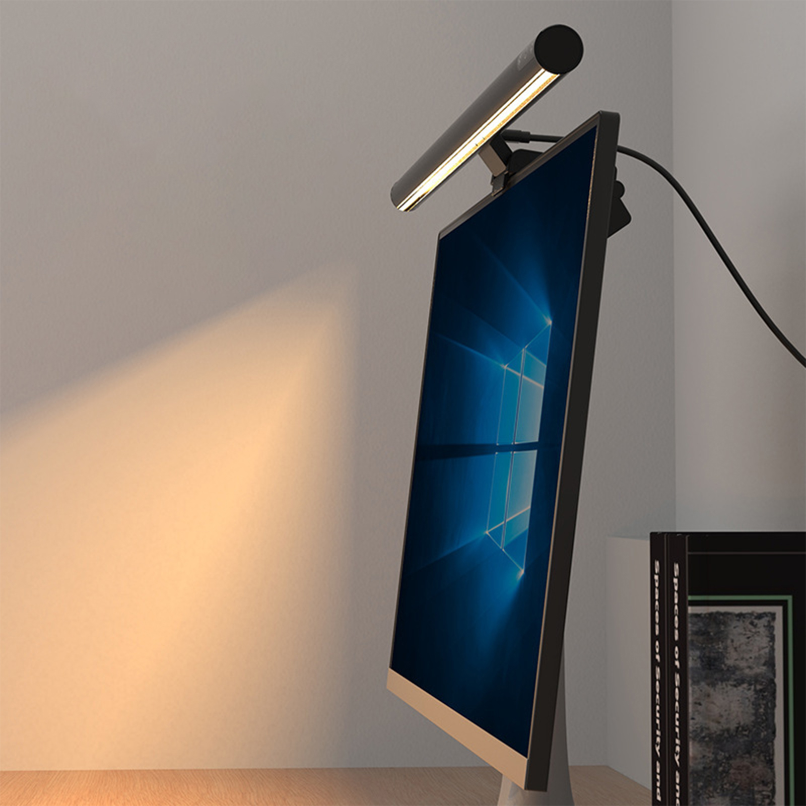 Ein Computermonitor mit einer schwarzen Lichtleiste oben, die einen warmen Schein an die Wand wirft.