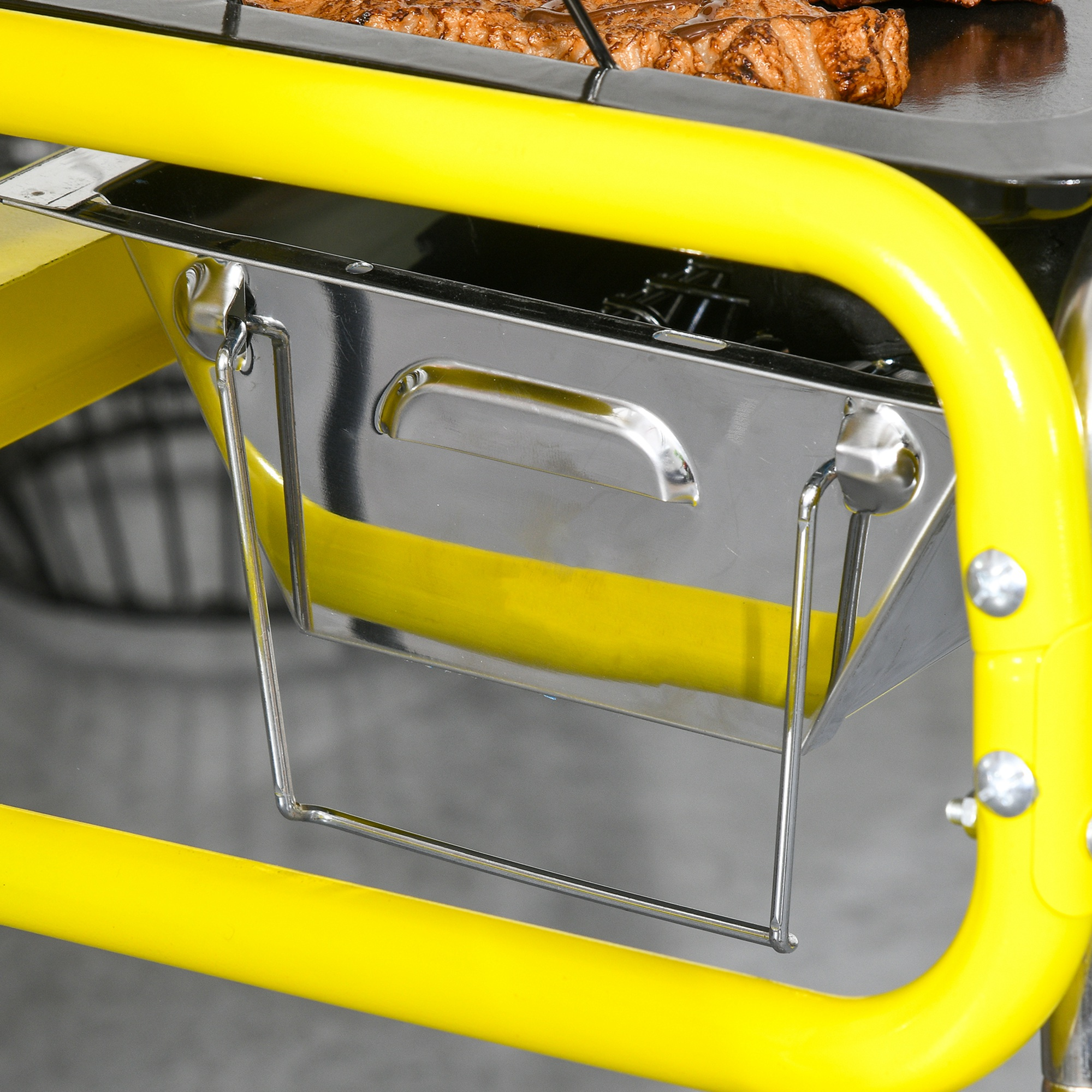 Eine gelbe Grillstruktur hält einen silbernen Behälter. Gegrilltes Essen ist sichtbar. Der Rahmen ist gelb.