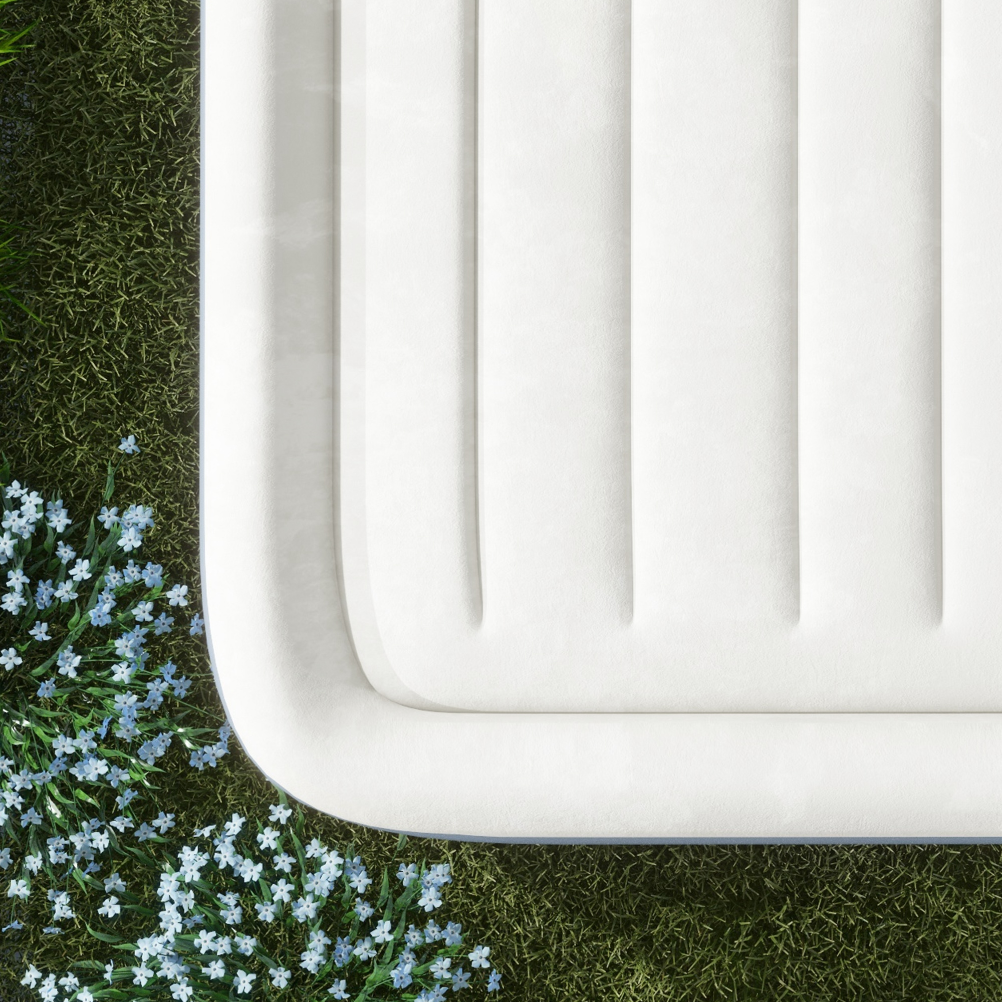 Weiße Matratze auf Gras mit blauen Blumen.