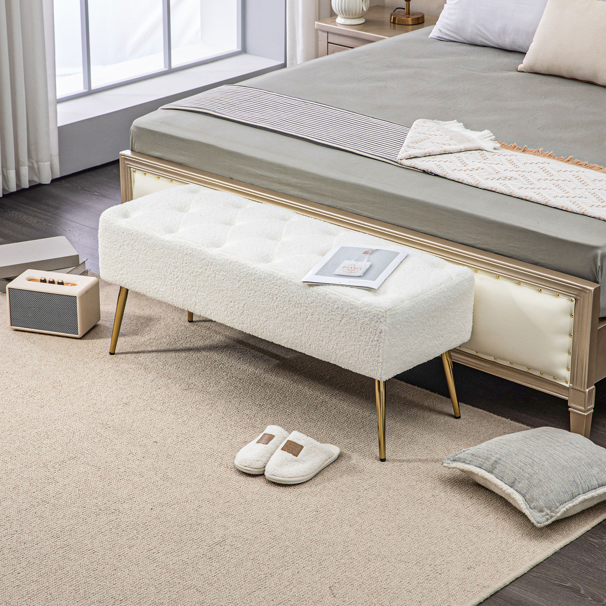 Schlafzimmer mit weißer Bank, Bett, Teppich und Lautsprechern.