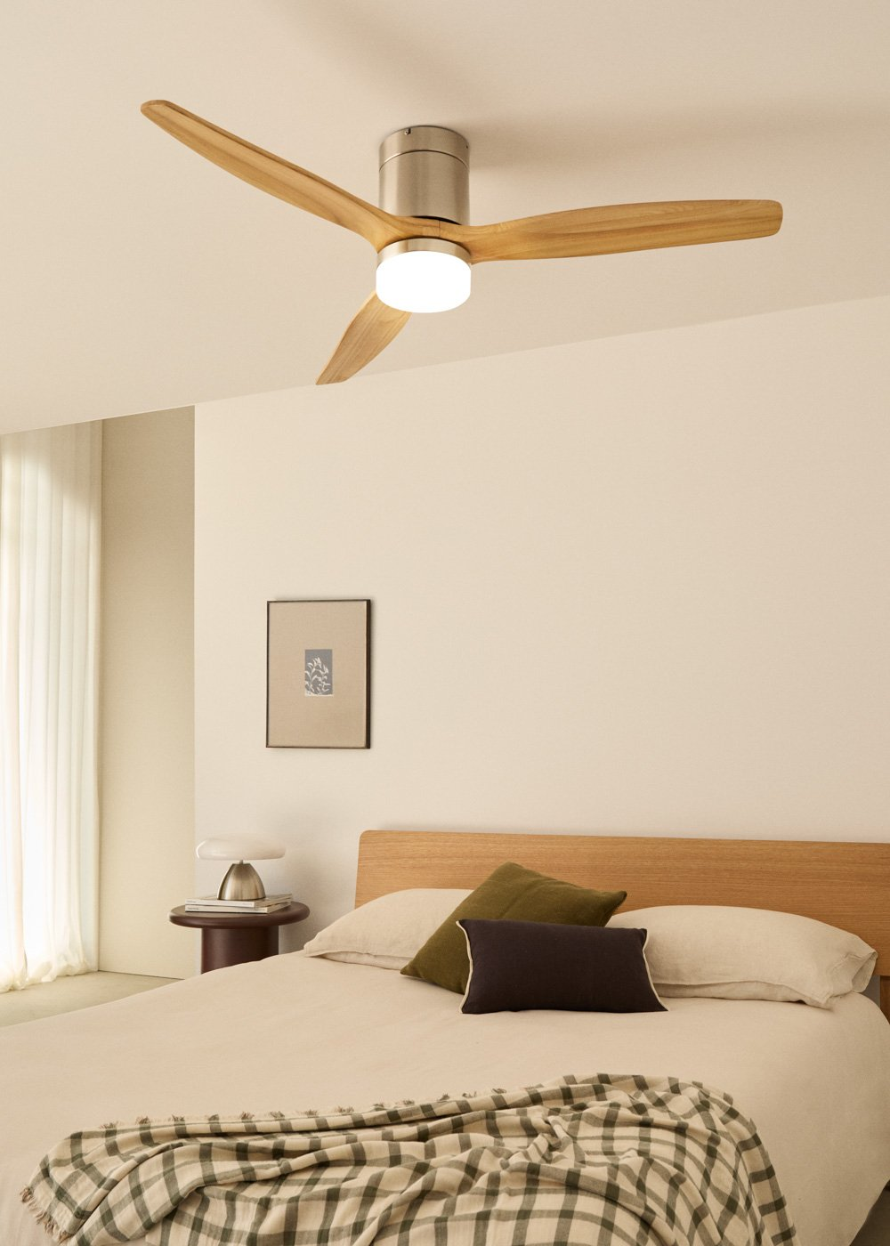 Un dormitorio con un ventilador de techo y una cama con almohadas y una manta.