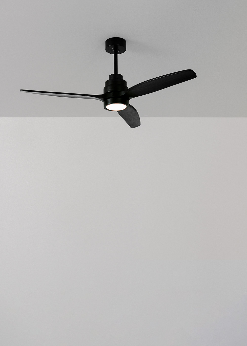 Ventilador de techo negro con 3 aspas. Las aspas tienen un diseño curvo y el techo es blanco.