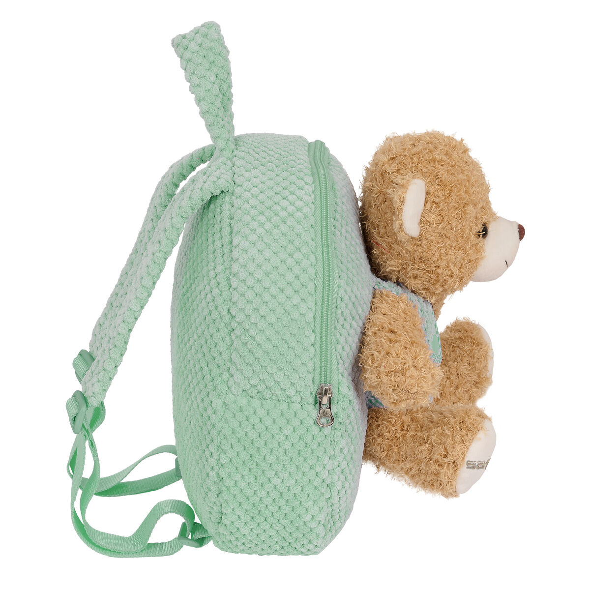 Ein grüner, strukturierter Rucksack mit einem Teddybären. Der Bär ist braun mit einem blauen Hemd.