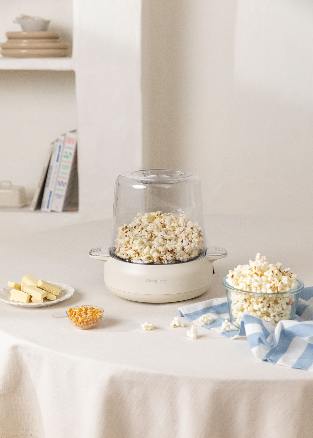 Máquina de palomitas con palomitas, mantequilla y granos de maíz en una mesa.