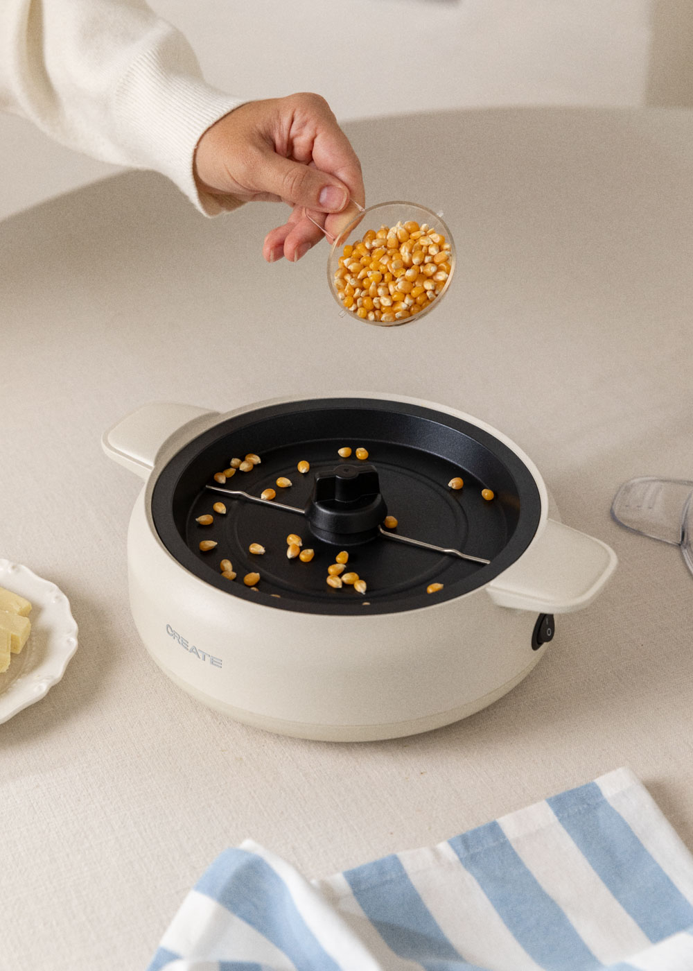 Granos de maíz vertidos en máquina de palomitas. Mantequilla y servilleta azul a la izquierda.