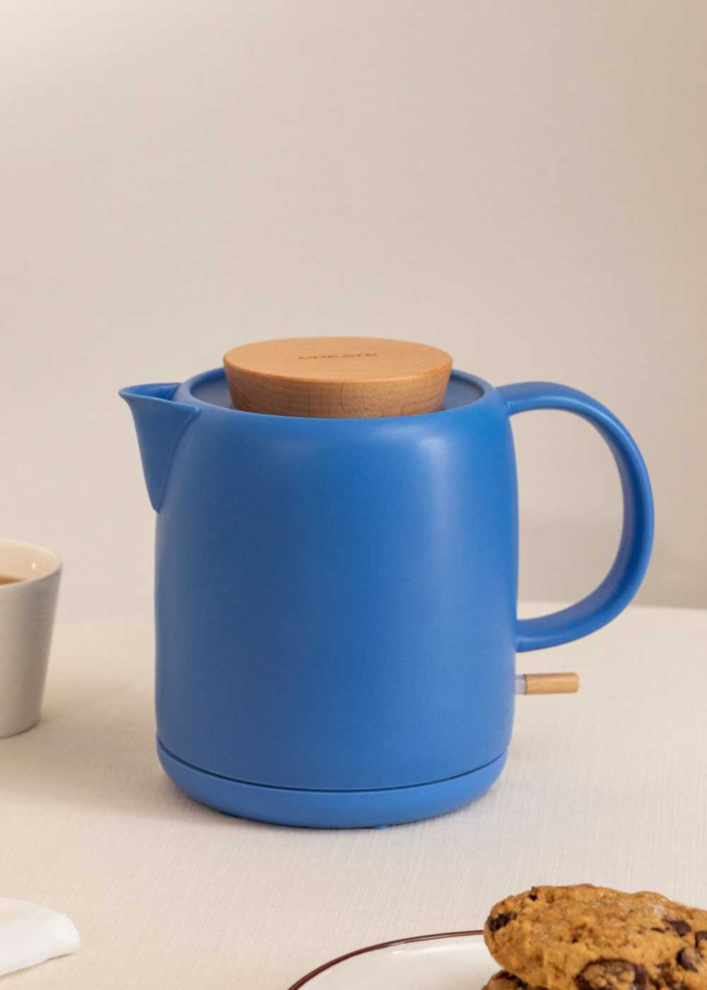 Una tetera eléctrica azul con tapa de madera y asa.