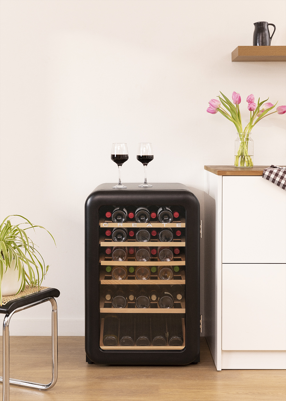Enfriador de vino negro con botellas y copas, fondo de cocina.