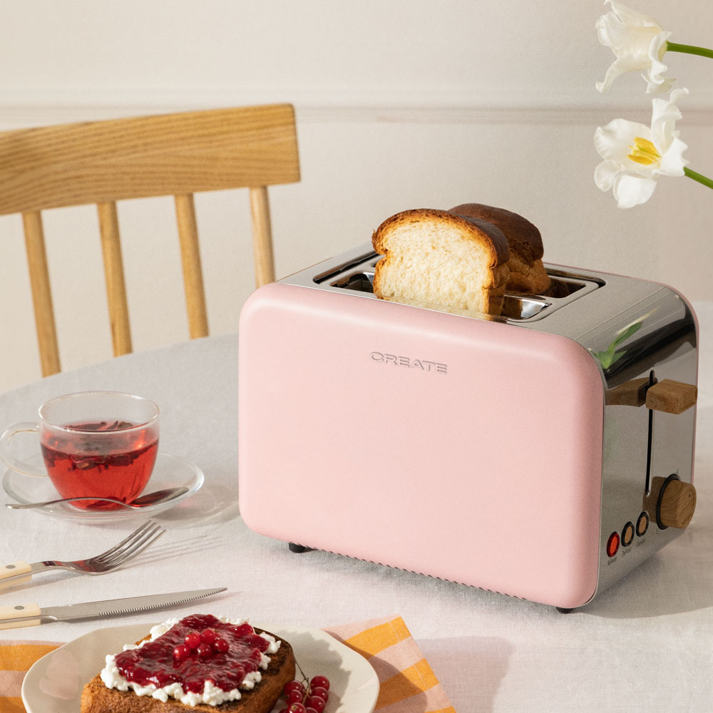Tostadora rosa con pan. Una taza de té y tostadas con mermelada. Flores blancas a la derecha.