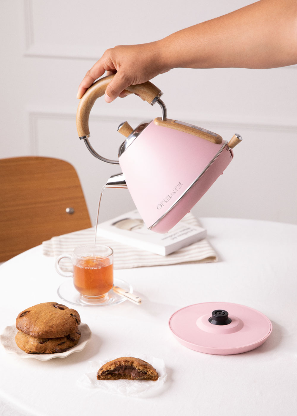 Pinker Wasserkocher gießt Wasser in ein Glas. Kekse und Wasserkocherboden.