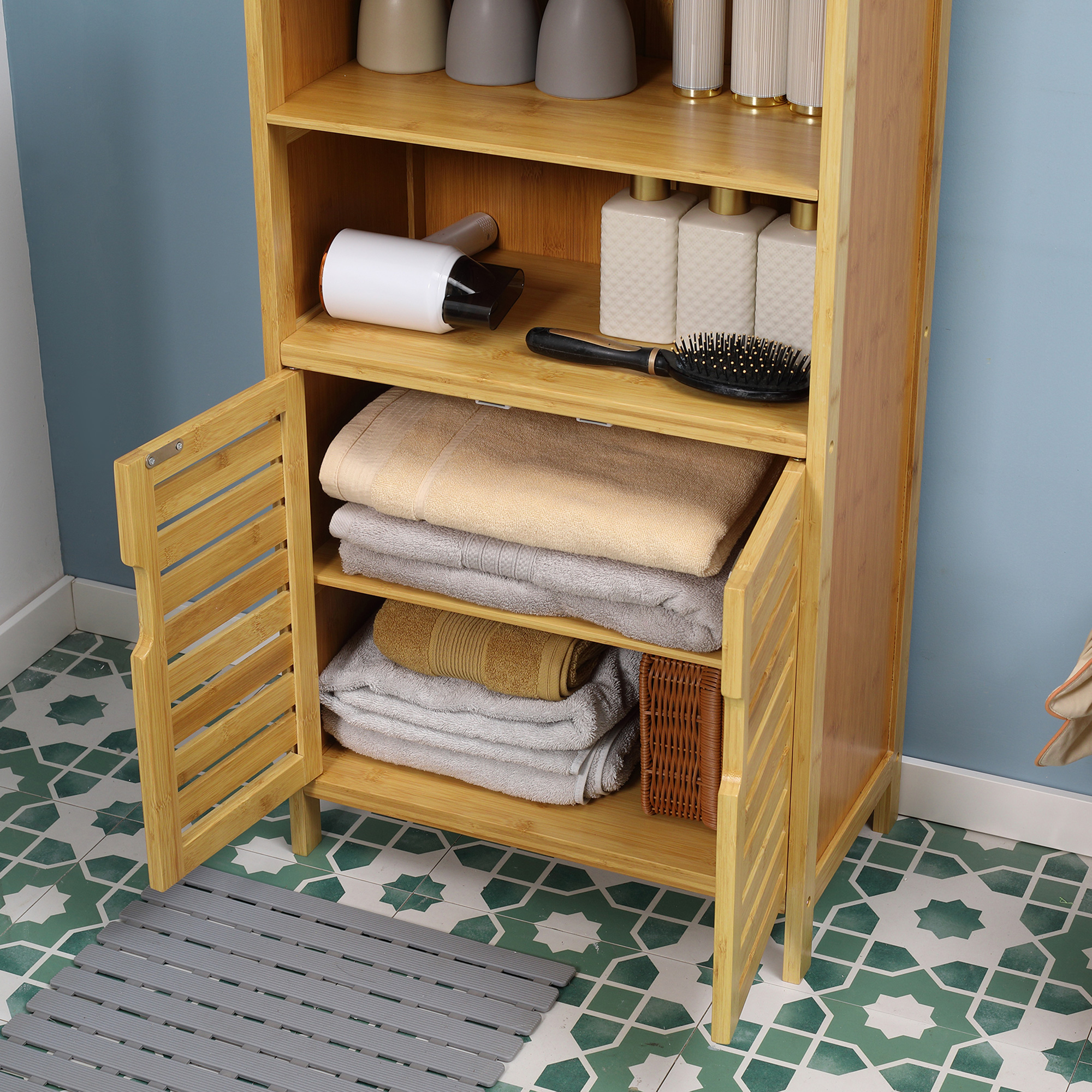 Ein Holzschrank mit offenen Türen, mit Handtüchern, einem Haartrockner und anderen Badezimmerartikeln.