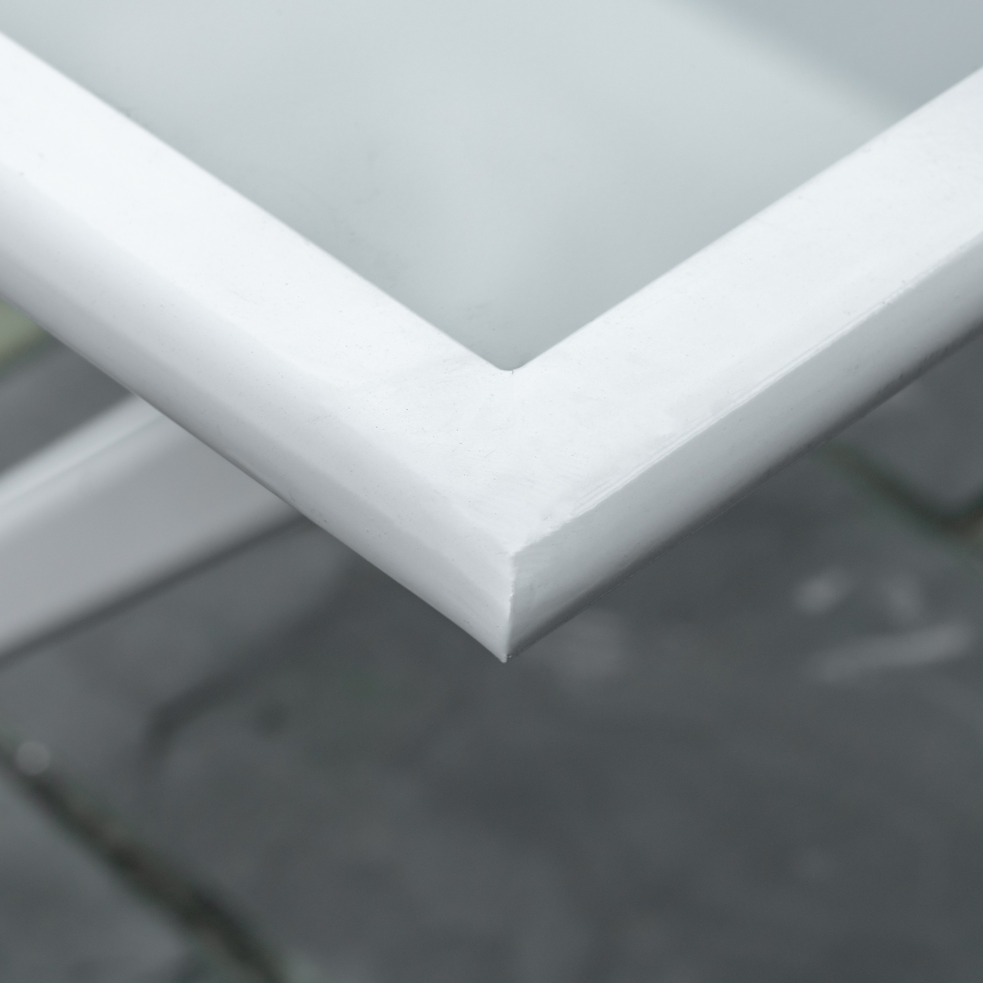 Nahaufnahme einer weißen Rahmenecke. Der Rahmen hat ein schlichtes Design mit leichtem Winkel.