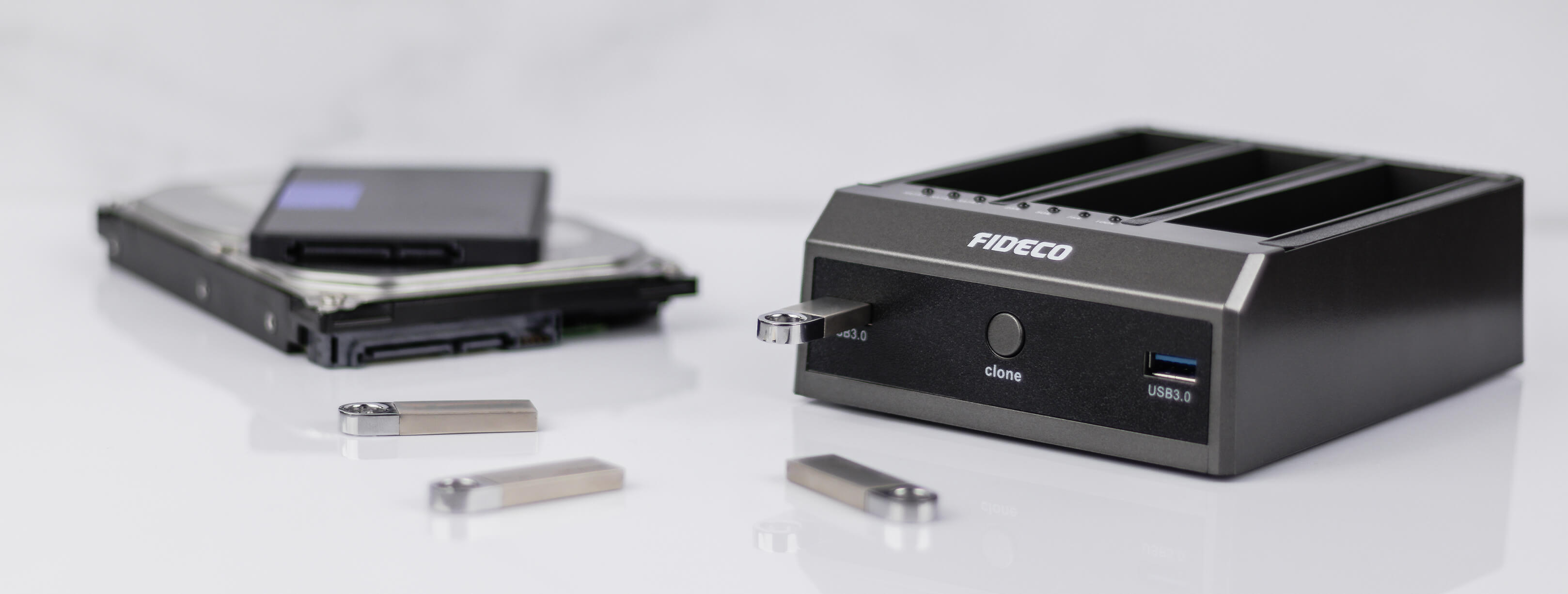 Dyski twarde, dyski USB i stacja dokująca na białej powierzchni.
