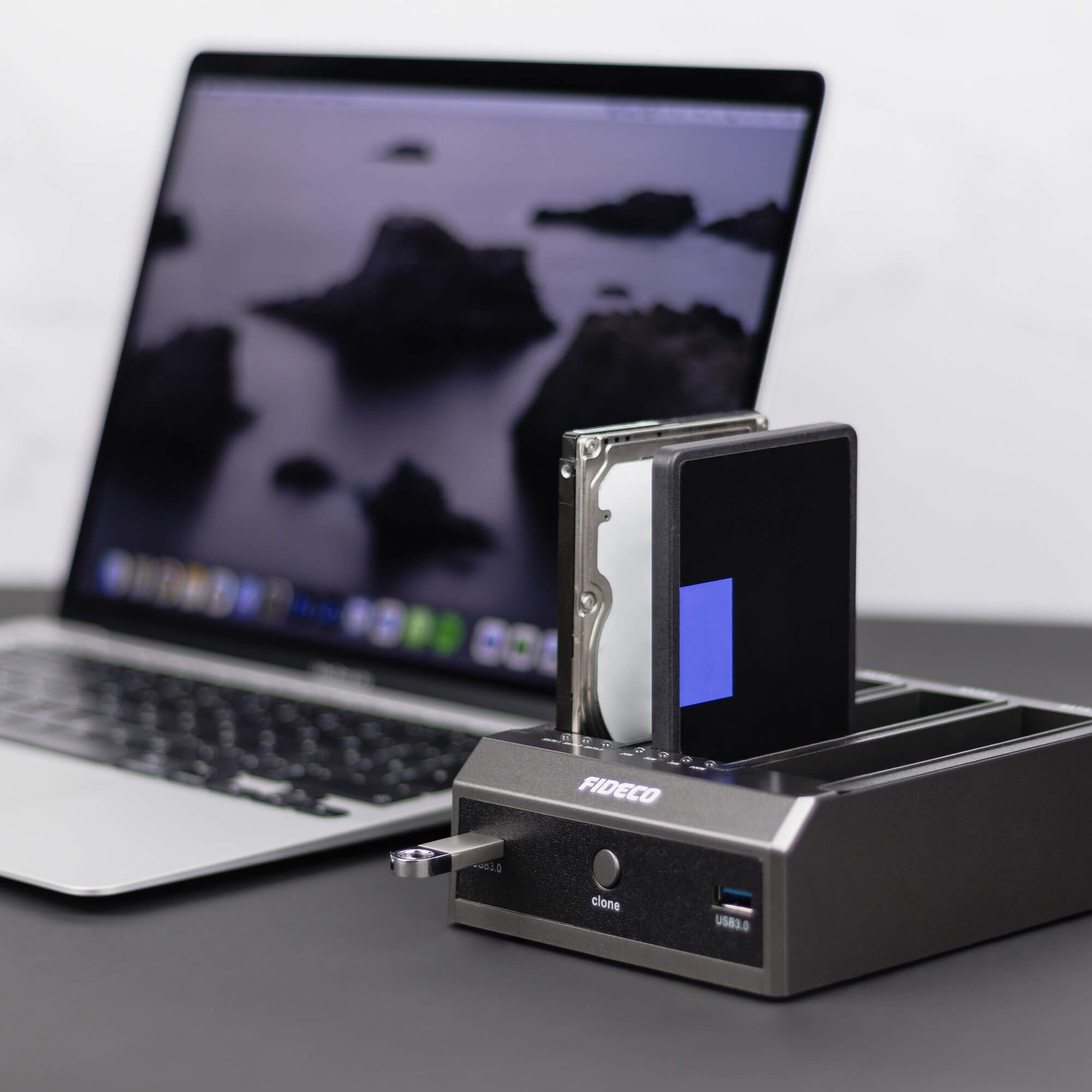 Stacja dokująca dysku twardego z laptopem i dyskiem twardym. Stacja jest srebrna i czarna.