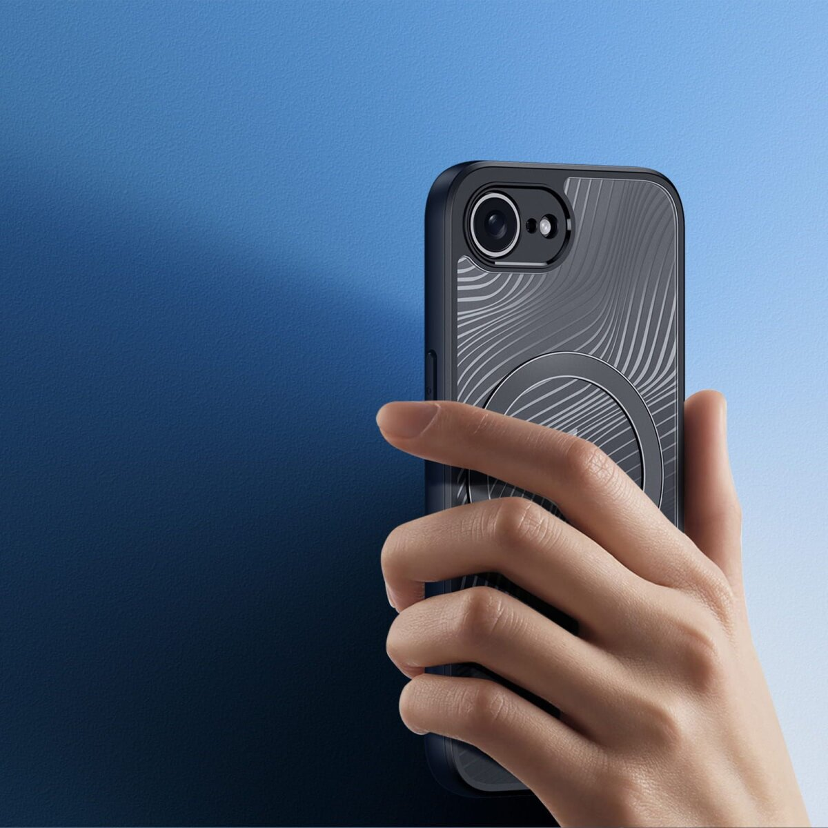 Hand hält ein schwarzes Telefon mit gemustertem Rücken vor blauem Hintergrund.