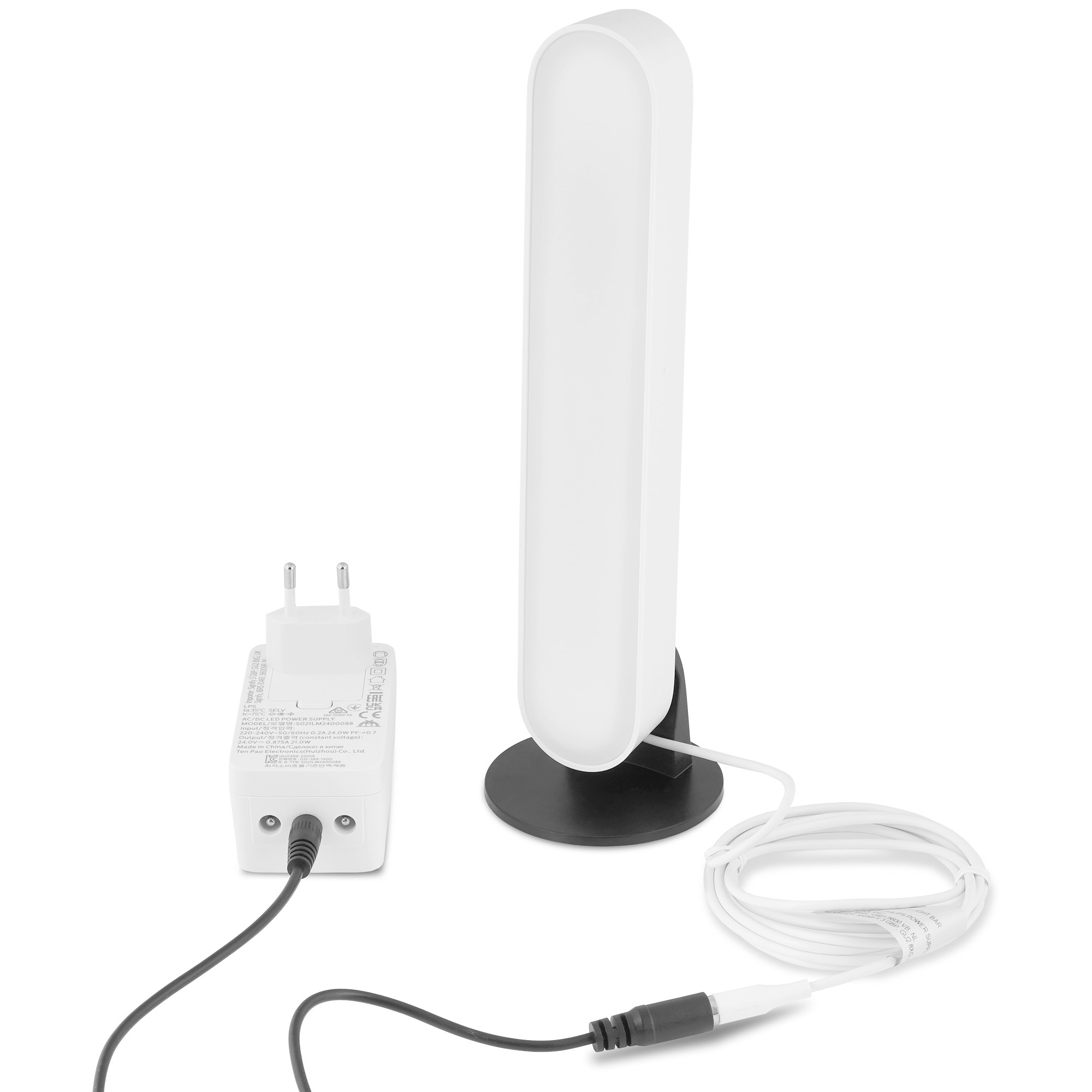 Eine weiße Lampe, ein Netzteil und ein Kabel. Die Lampe hat einen schwarzen Sockel.