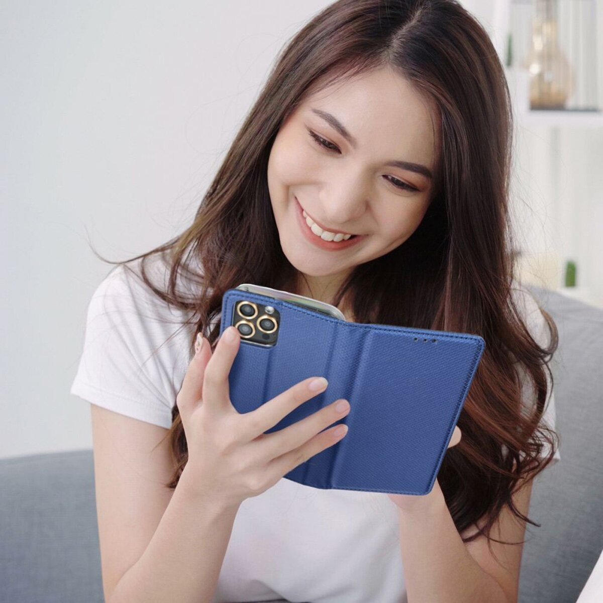Eine lächelnde Frau, die auf ein Telefon in einem blauen Case schaut.