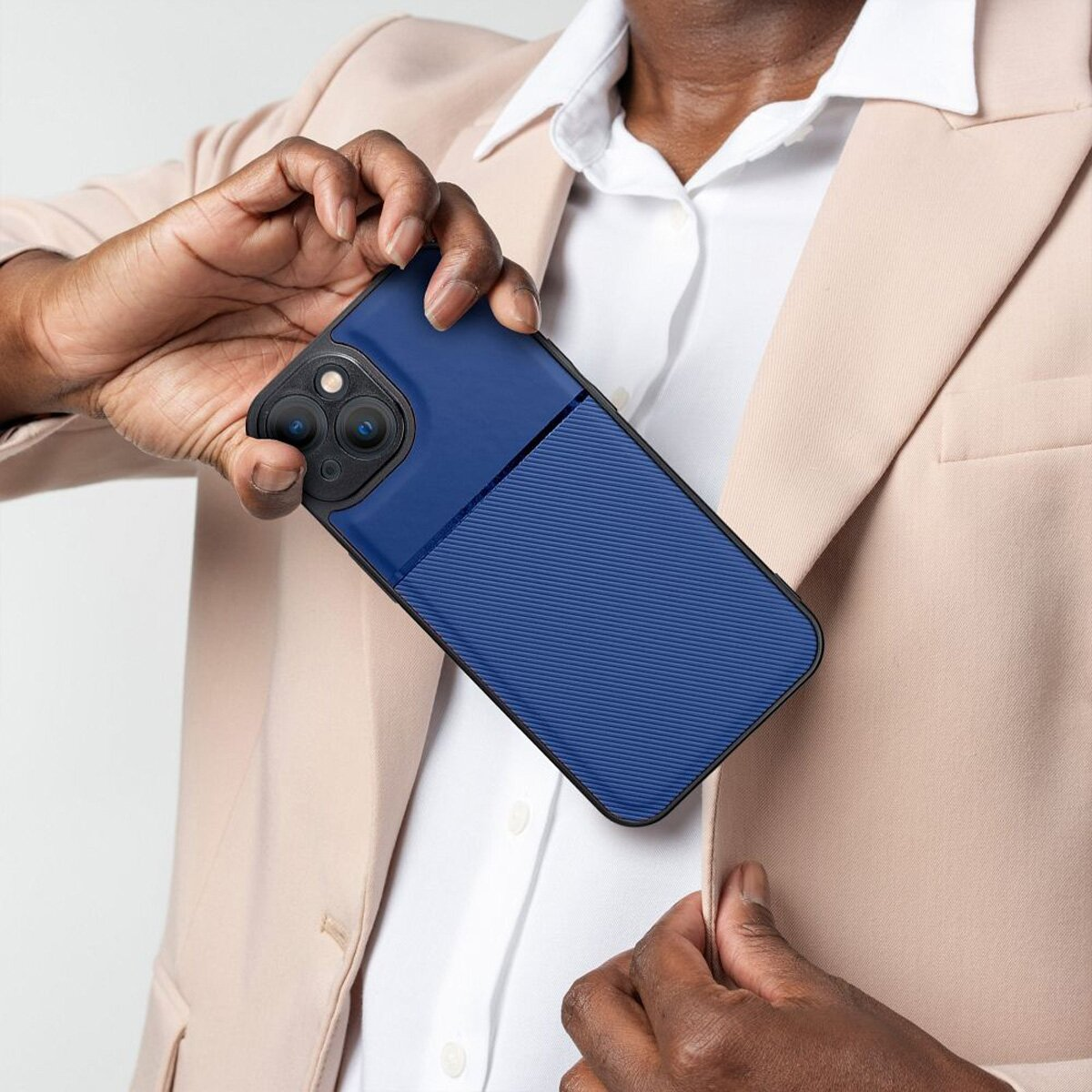 Eine Person hält eine blau-schwarze Handyhülle, mit einer Jacke im Hintergrund.