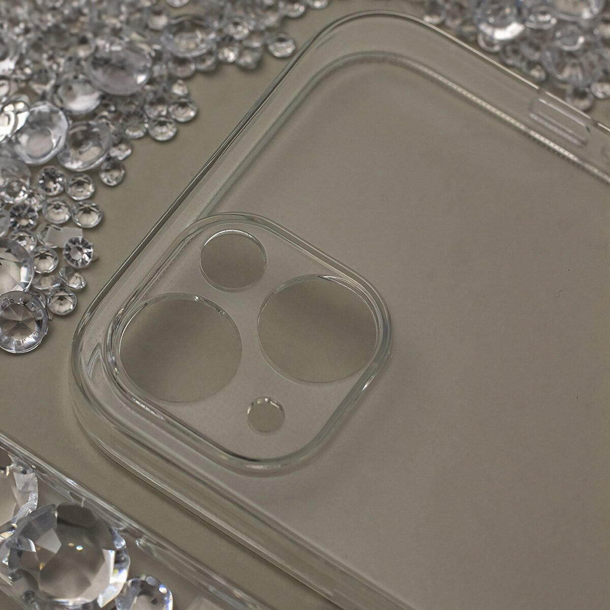 Eine transparente Handyhülle mit Strasssteinen um die Kamera.