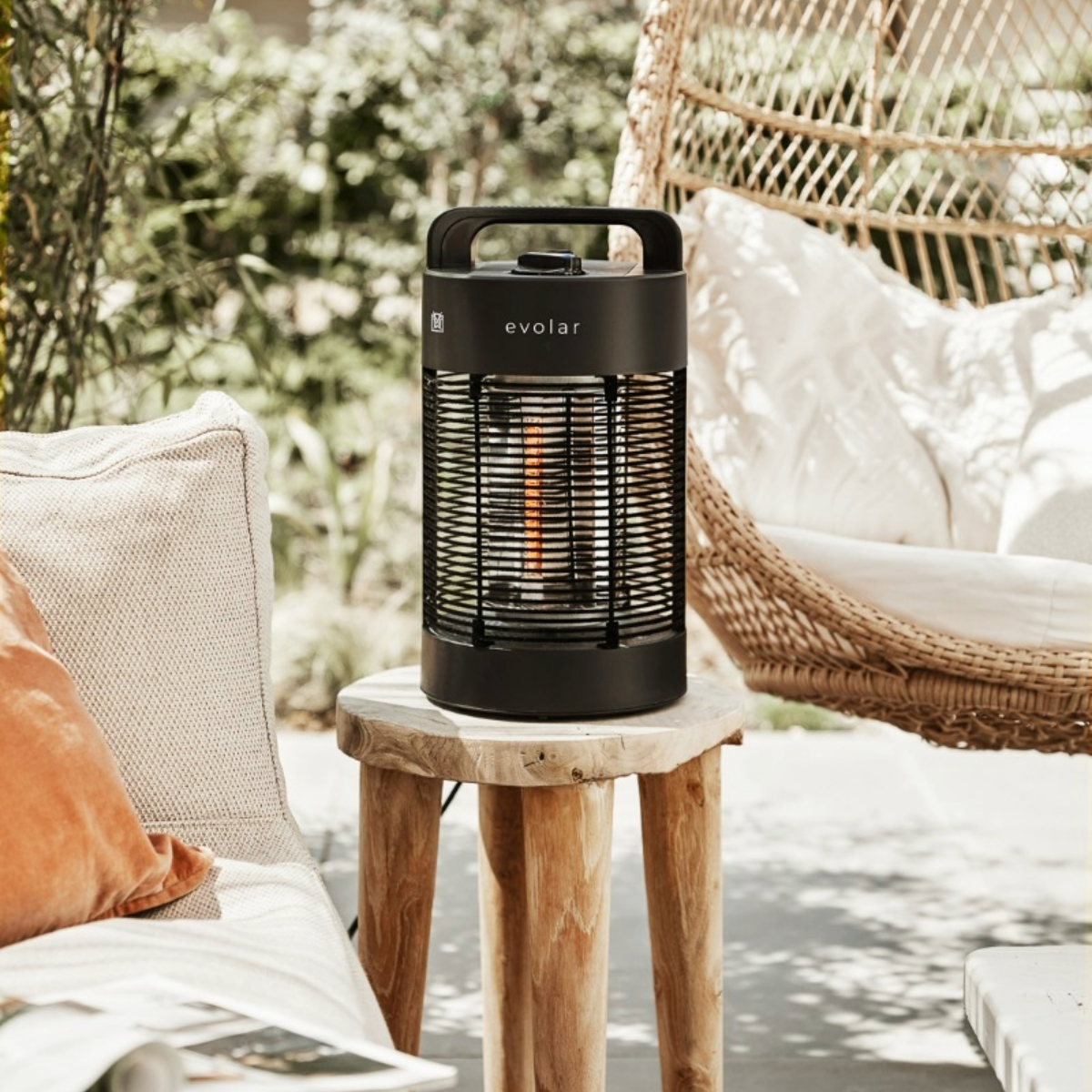 Riscaldatore elettrico esterno Evolar nero su sgabello in legno. Sedia sospesa sullo sfondo.